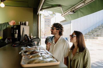 A man and a woman stand at the counter and listen to the salesperson