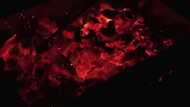 Slow motion closeup of hot charcoal in dark environment
