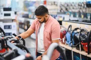 Fototapeta premium An Indian man is choosing a new vacuum cleaner in an electronics store