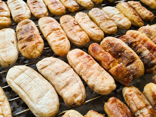 Thai Street Food Whole Kluay Ping Bananas Grilling on Charcoal Metal Grate Close Up Texture