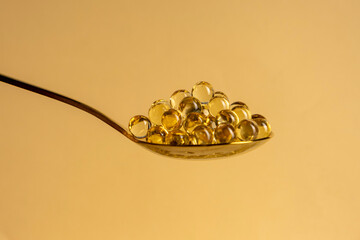 Capsules of vitamin D3 on a yellow background with free space. Biologically active substances of the calciferol group are fat-soluble organic compounds.