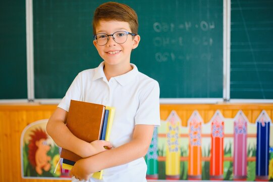 Funny schoolboy near the green school board in the classroom. Elementary school. Back to school