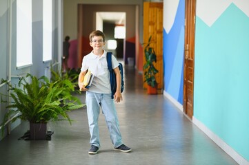 Schoolboy with schoolbag and books in the school. Education concept. Back to school. Schoolkid going to class. Stylish boy with backpack. Boy ready to study