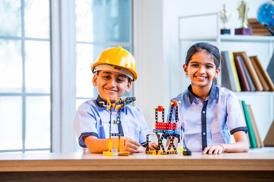 Indian Students in uniform hard hats study crane mechanism with 3D model during classroom activity
