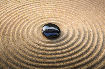 Zen Garden Sand Ripples Centered Around a Single Black Polished Stone
