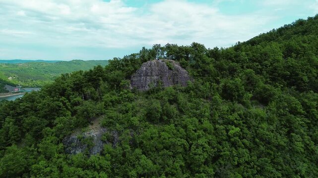 Drone view of Velika Stena viewpoint in Serbia, a rocky cliff surrounded by lush green forest and scenic hills. Horizontal 4k footage