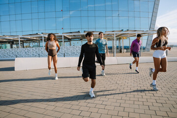 A group of five athletes running in place with their legs thrown back