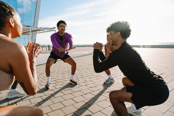 A group of five athletes squatting in a circle