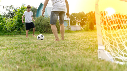 Grandfather and grandson playing football near the house