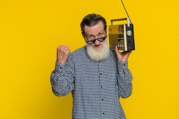 Senior old man using retro tape record player to listen music, disco dancing favorite track, having...