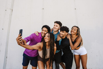 A group of five athletes smile and pose in front of a phone held by one of them
