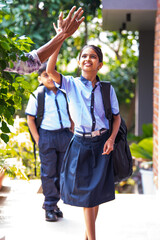 Indian School kids greeting teacher with hi-five while entering school in uniform happily