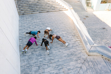 A group of five athletes stand in a push-up position in a circle and bend their legs