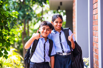 Indian Cheerful school kids in uniform smile at camera while standing outdoors on a sunny school day