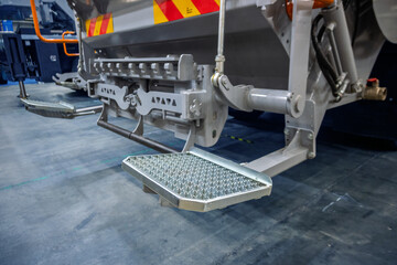Fototapeta premium Close-up of industrial vehicle's heavy-duty metal steps and robust machinery, featuring anti-slip treads and hydraulic components. Ideal for themes of infrastructure, maintenance, and heavy equipment.