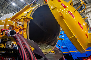 Close-up of a powerful industrial sewer cleaning truck with its rear tank door open, revealing the...