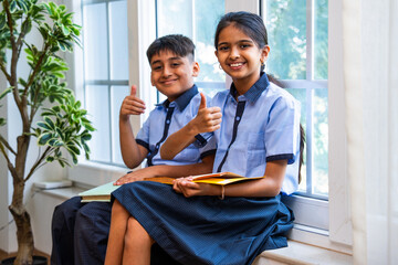 Indian Uniformed students quietly read near classroom window during peaceful self-study time