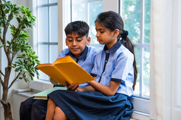 Indian Uniformed students quietly read near classroom window during peaceful self-study time