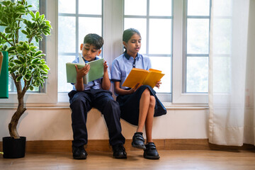 Indian Uniformed students quietly read near classroom window during peaceful self-study time
