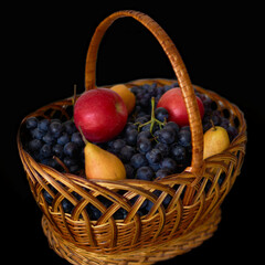 Fruits in a wicker basket on a black background closeup