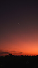 A morning scene with a warm orange sunrise and the moon still visible, creating a serene and magical atmosphere.