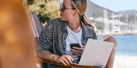Beach workation digital nomad plans tasks with laptop and notebook on lounge chairs, powered by a...