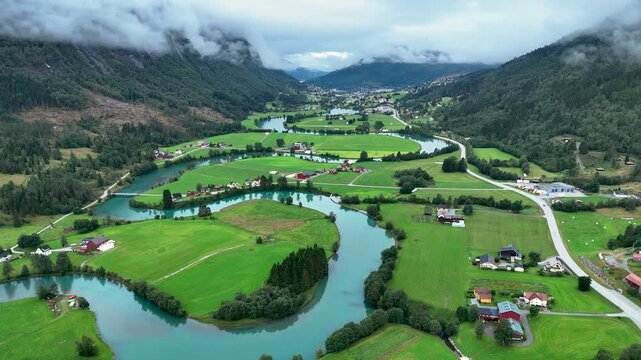 Explore the stunning greenery and meandering rivers in Stryn, Norway. This picturesque landscape features gentle hills, charming homes, and a serene atmosphere, perfect for nature lovers.