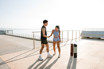 Male and female athletes shaking hands and talking while standing and laughing