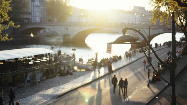 People walking along the seine river in paris at sunset