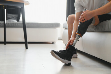 Closeup of unrecognizable man with bionic prosthetic leg at home indoors, copy space