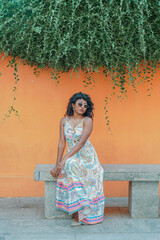 Fototapeta premium A woman is sitting on a bench wearing a white dress