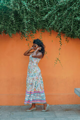 Fototapeta premium A woman in a white dress stands in front of a wall with green vines