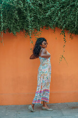 Obraz premium A woman in a floral dress stands in front of a wall