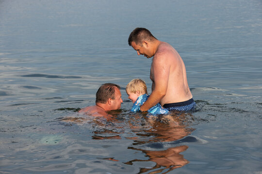 Two men and a child playing in the water