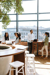 A group of four workers stand in pairs at tables and talk