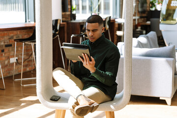 A male worker looks at a computer tablet while sitting on a chair