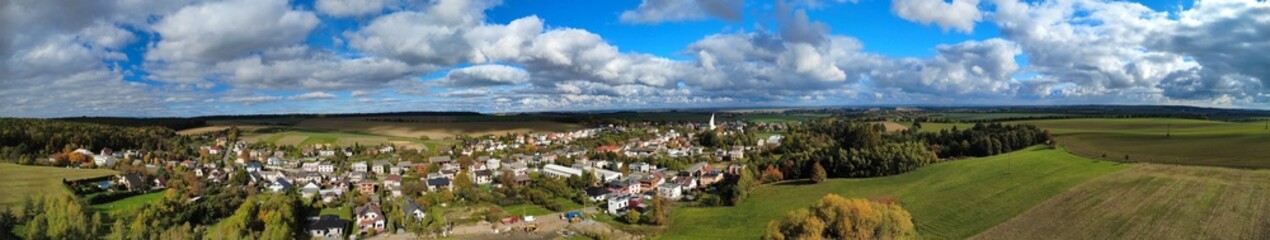 Panoramic aerial view of a village on a sunny autumn day. The colorful trees, fields, and rooftops create a peaceful and vibrant rural landscape, capturing the beauty of the Czech countryside in fall.