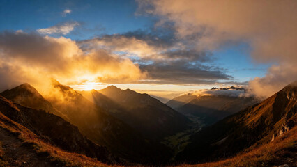 Sunrise over mountain range with golden light illuminating clouds and peaks