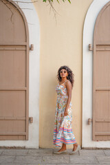 Fototapeta premium A woman in a white dress stands in front of a building with a tan wall
