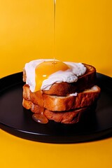 Gourmet French Toast Stack Topped with Poached Egg and Pouring Golden Honey on a Black Plate
