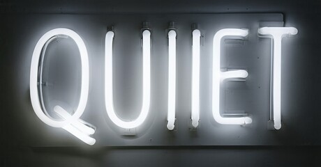 Bright neon sign spells QUIET. Minimalist aesthetic, stark contrast, simple typography. Wall background provides neutral space.