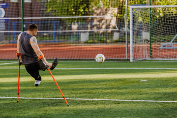 A man leans on crutches on the field after hitting the ball into the goal