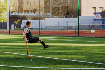 A man leans on crutches after kicking a ball