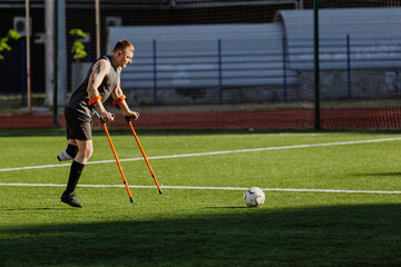 A man on crutches is running after a ball in front of him