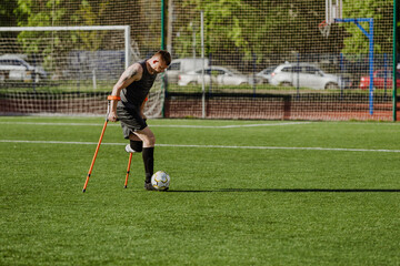 Obraz premium Man dribbles ball with foot and runs while holding crutches