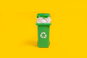 Garbage can with paper on a yellow background. Garbage recycling