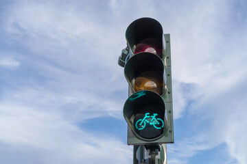 Green bicycle traffic light in the city against blue sky