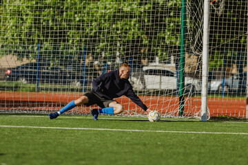 A man caught the ball with his hand as it fell onto the field near the goal