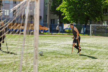 A man on crutches runs to kick the ball into the goal
