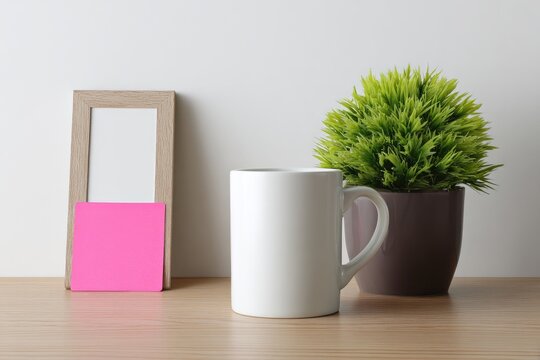Blank wooden frame, pink sticky note, white mug, and small plant on light wooden surface - Powered by Adobe